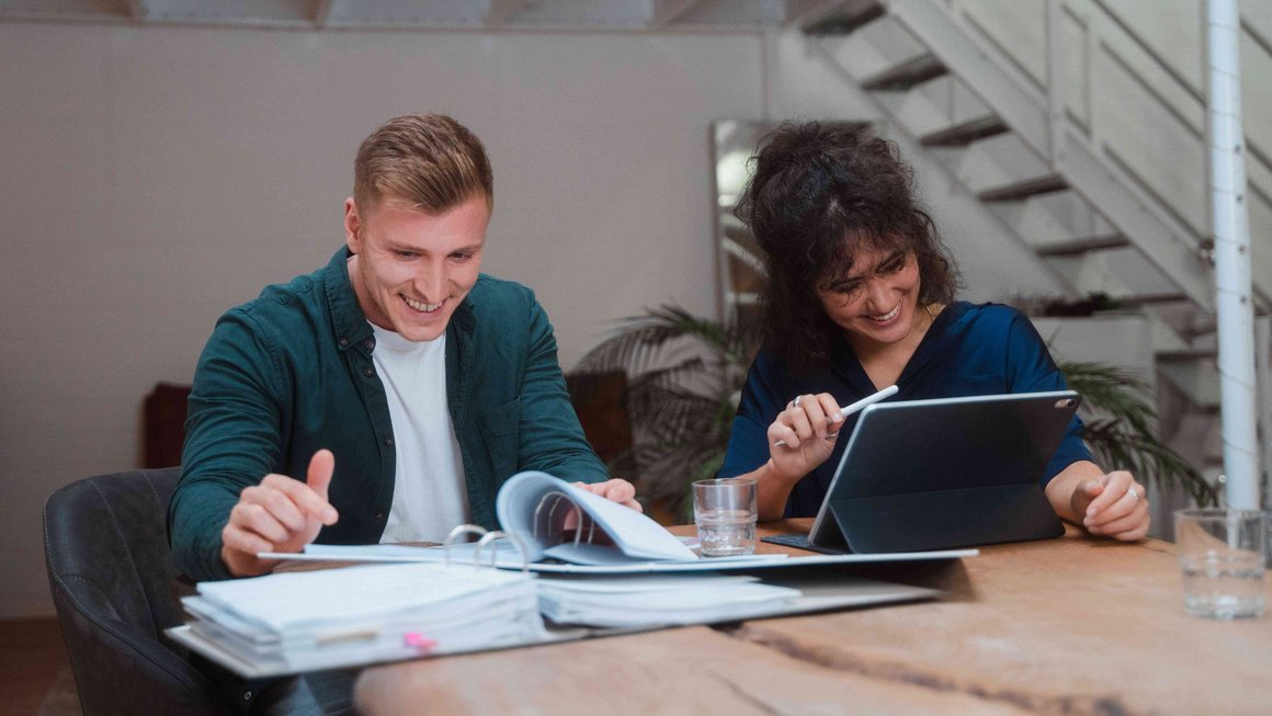 Un jeune couple travaille ensemble sur le carnet de gestion financière du foyer