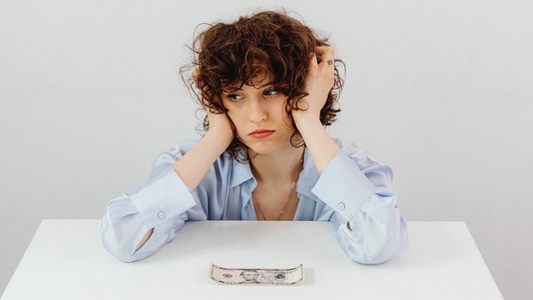 Une femme fait la moue devant un billet de banque – économiser de l’électricité Une femme fait la moue devant un billet de banque – économiser de l’électricité