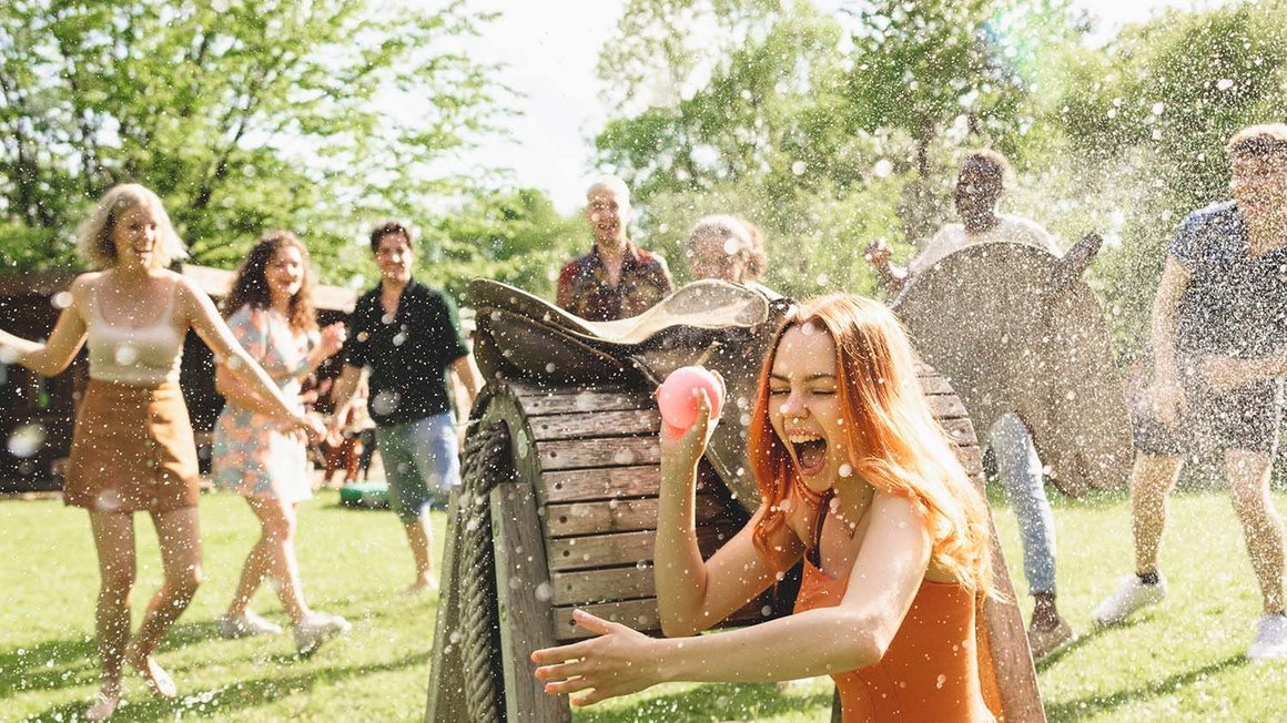 Un groupe de jeunes s’amusent avec de l’eau pendant qu’une femme se cache