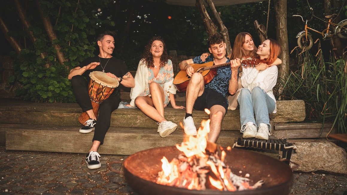 Des jeunes assis autour d’un feu de camp l’aventure en van