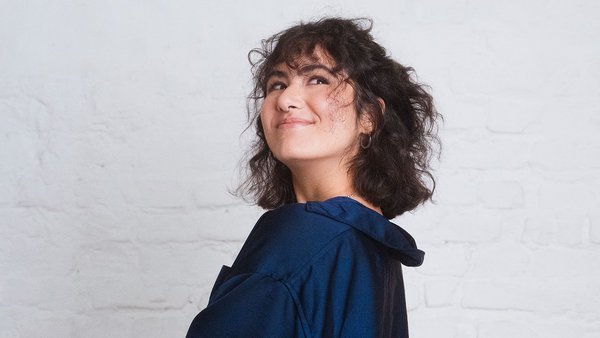 La règle des 50-30-20 fonctionne-t-elle aussi avec un petit salaire ? Une femme avec un haut bleu et des cheveux bruns regarde en l’air avec un air malicieux.