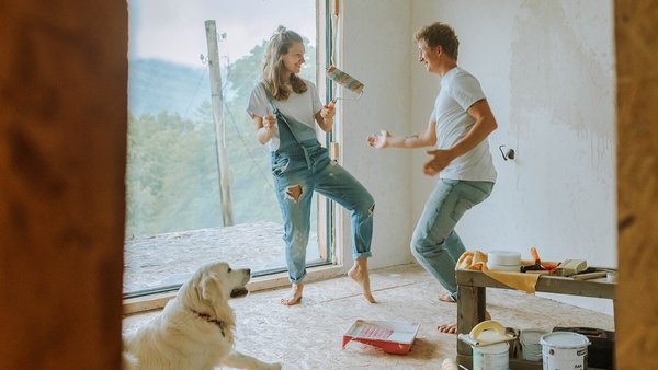 Un couple danse avec leur chien dans leur nouvelle maison – Financement immobilier