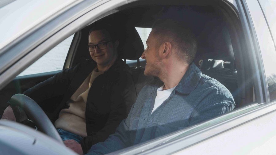 Deux jeunes hommes assis dans une voiture se sourient