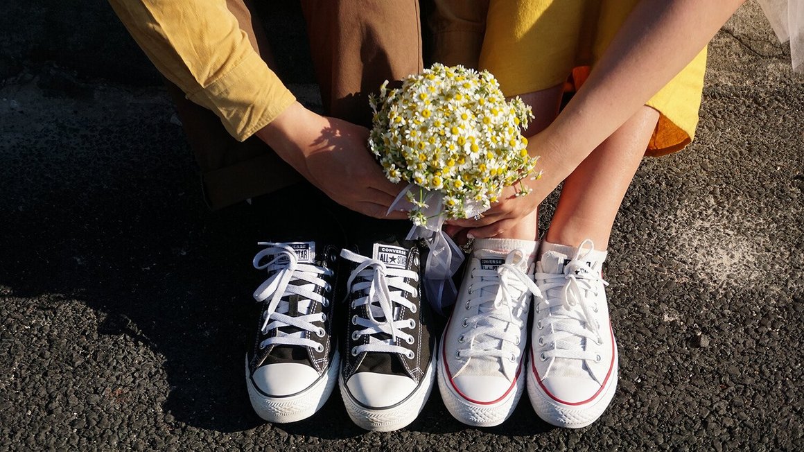 Un couple est assis au sol avec des fleurs dans les mains – Planification mariage
