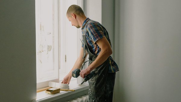 Un homme répare une fenêtre - assurance accidents professionnels et invalidité Un homme répare une fenêtre - assurance accidents professionnels et invalidité