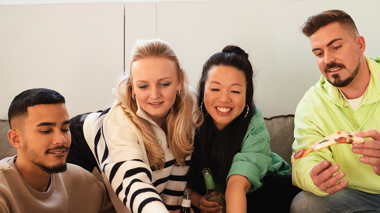 Quatre jeunes adultes rigolent assis sur un canapé