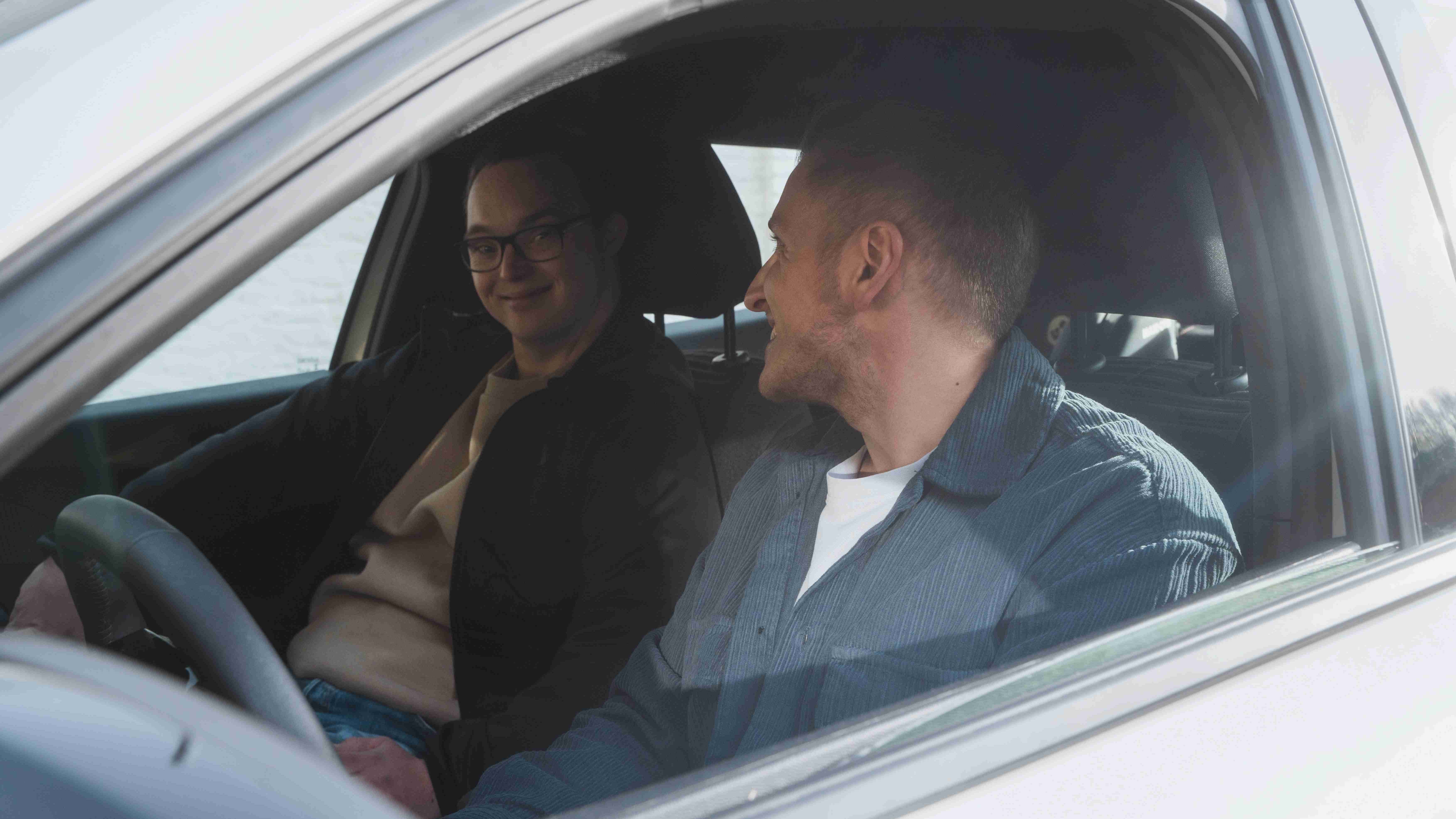 Est-ce que l’achat d’une voiture a du sens ? Deux jeunes hommes assis dans une voiture se sourient
