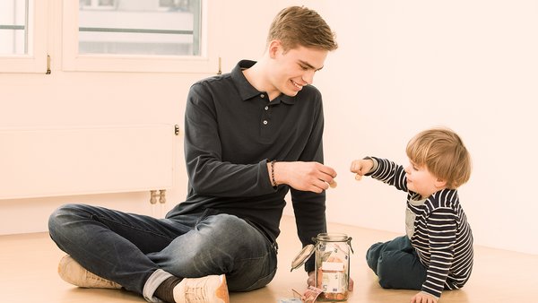Un enfant et un jeune homme épargnent de l’argent dans un pot Un enfant et un jeune homme épargnent de l’argent dans un pot