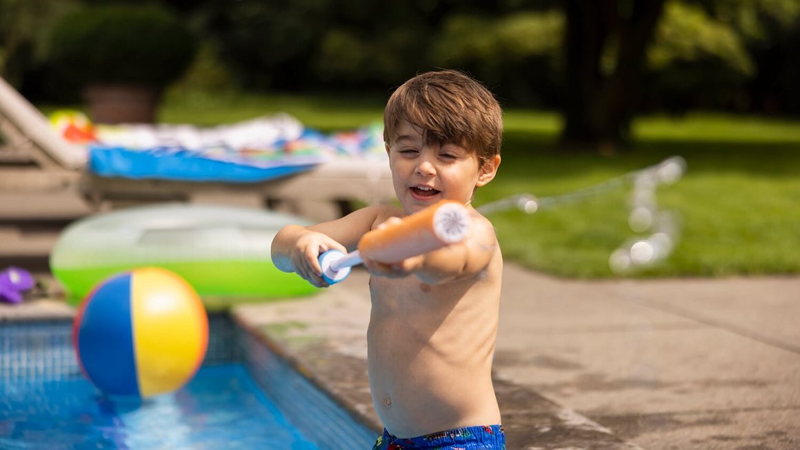 Enfant à la piscine avec un pistolet à eau – Voyager en sûreté